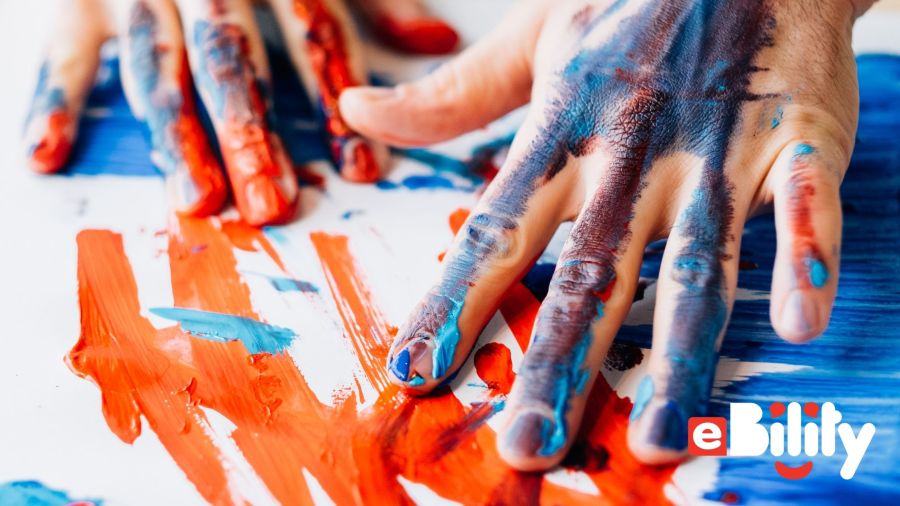 hands and paper covered in blue and orange paint. eBility