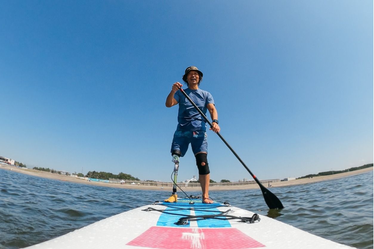 Image of amputee with prosthetic leg on a stand up paddle board.