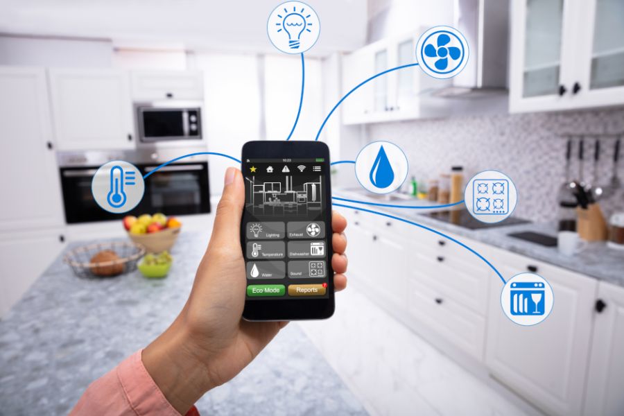 Image of person's hand holding a smartphone in a kitchen.
